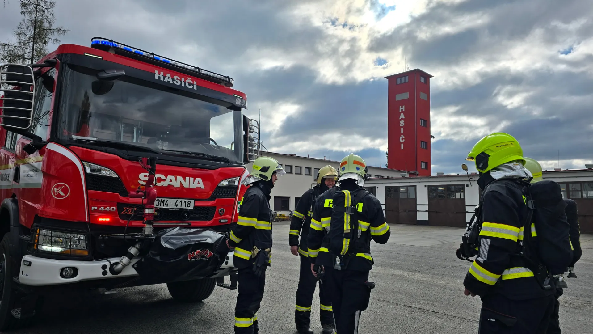 Členové JSDH v zásahových oblecích u cisternové automobilové stříkačky Scania před hasičskou zbrojnicí